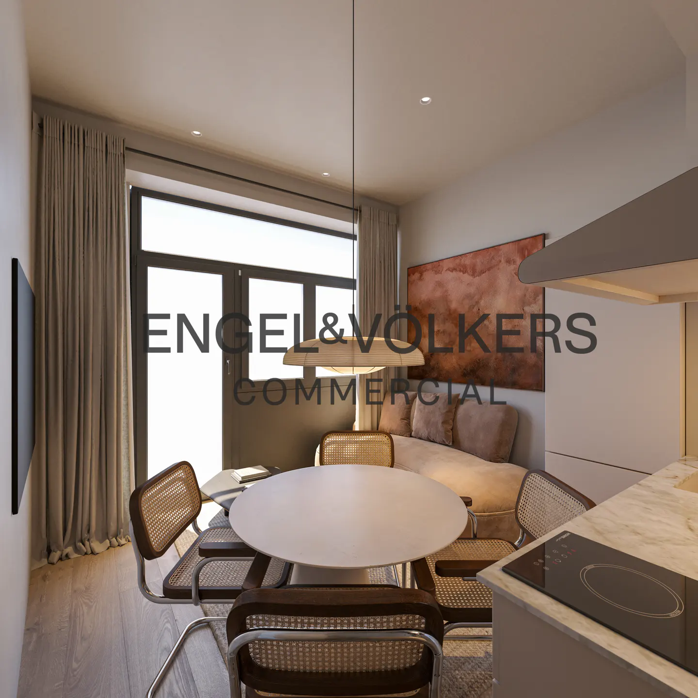 Modern apartment interior with a round white table surrounded by wicker chairs, a beige sofa, and a kitchen counter with a black stovetop.
