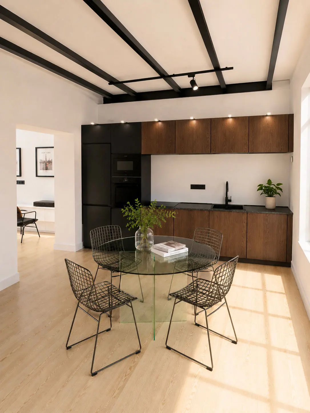Modern kitchen with wood cabinets, black appliances, and a glass dining table with four black wire chairs on light flooring.
