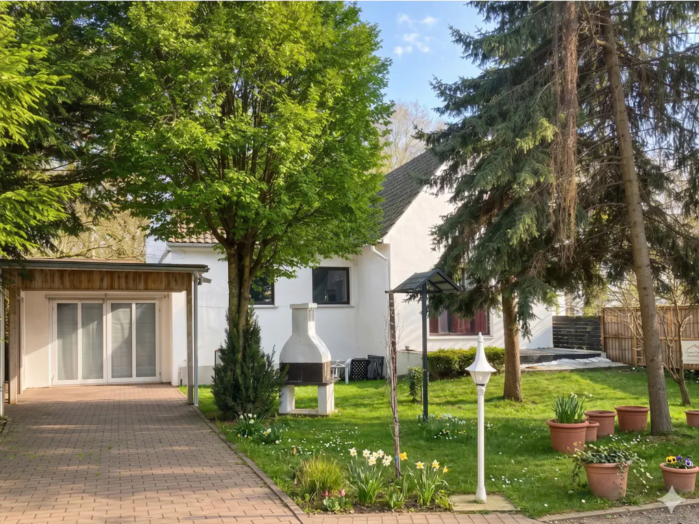 Exterior of a white house with a brick driveway, green lawn, trees, and potted plants.