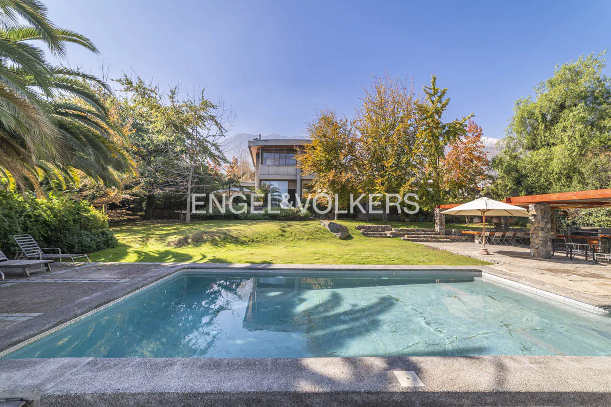 A wide shot of a pool in front of a modern house with the Engel & Volkers logo on the lawn.