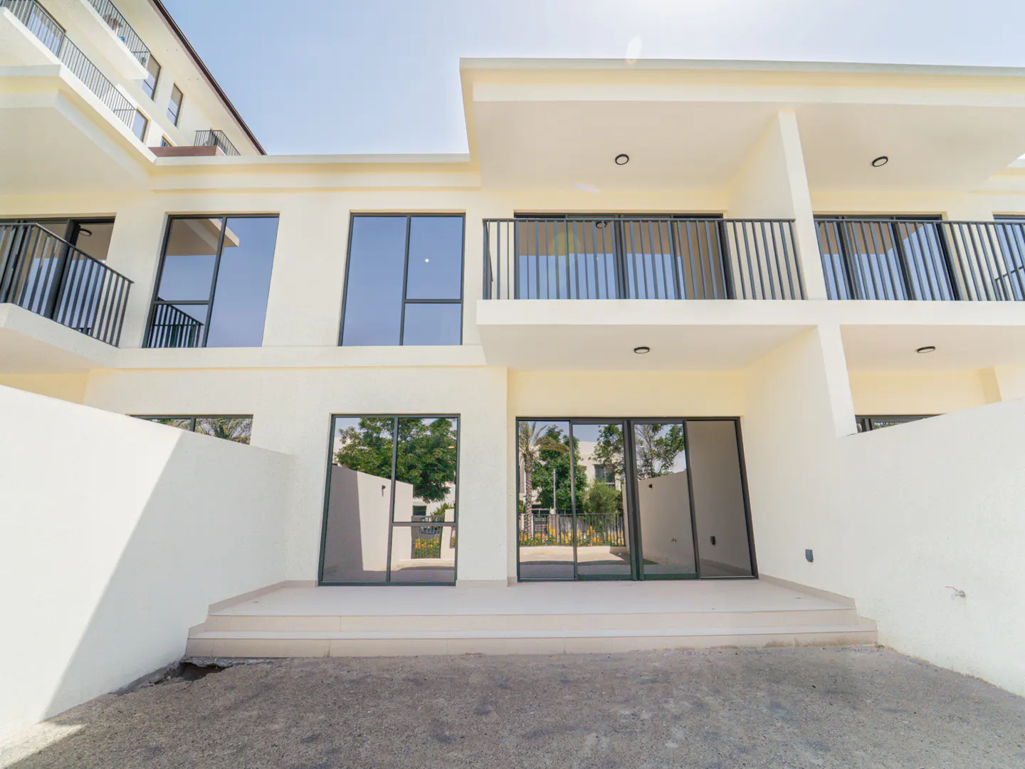 Exterior view of a modern, two-story townhouse with a white facade, black window frames, and balconies.