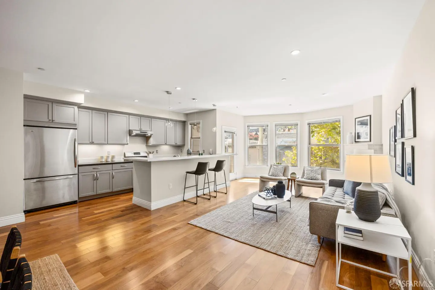 Open-concept kitchen and living area with gray cabinets, hardwood floors, a breakfast bar, and a cozy seating area.