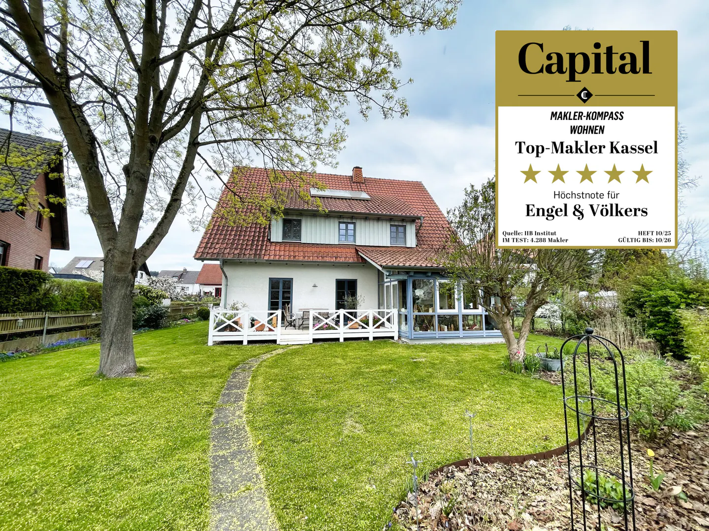 A white two-story house with a red tile roof and a sunroom, viewed from the lawn. A Capital award logo is in the upper right corner.