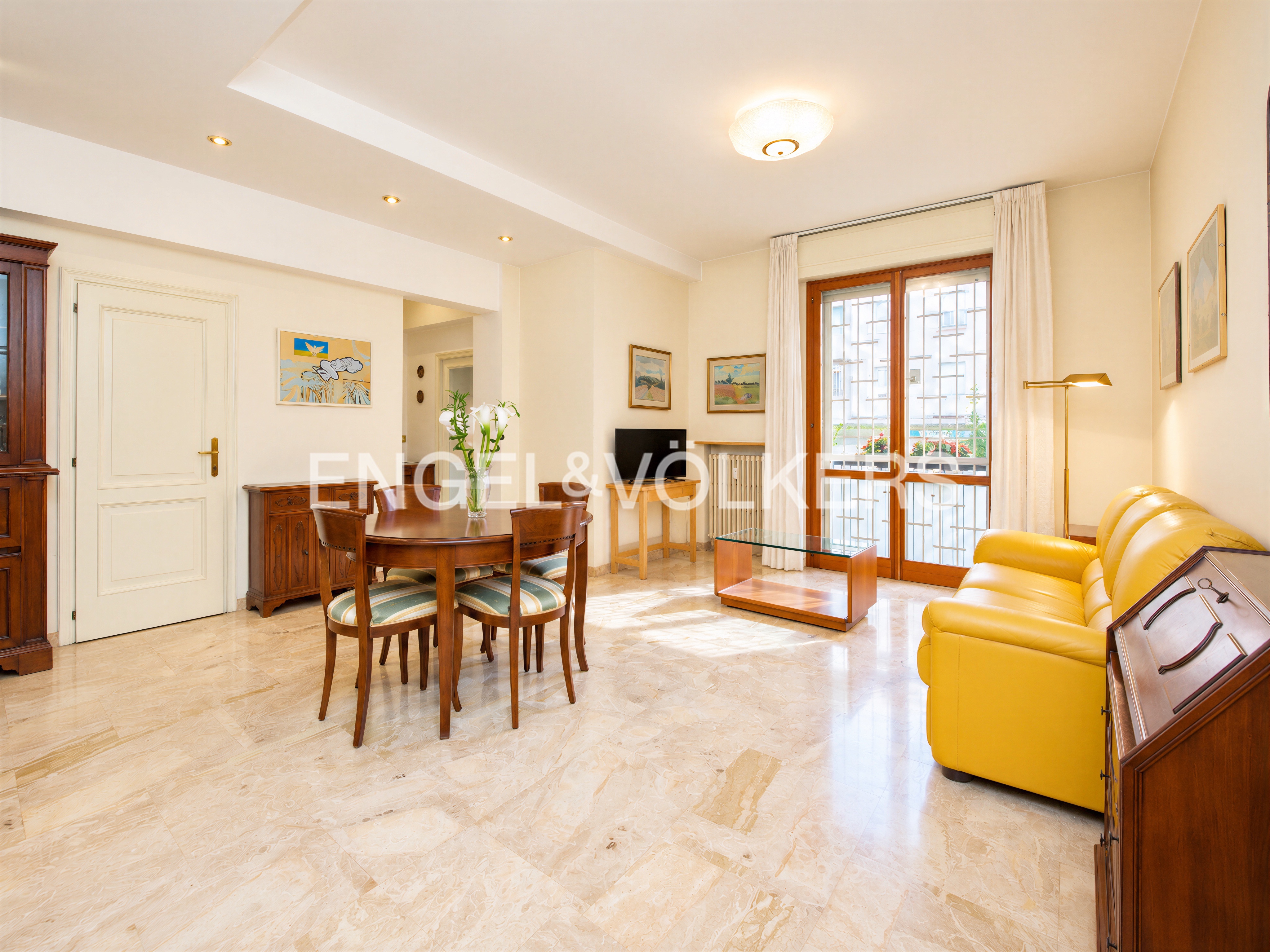 Bright living room with marble floors, a yellow leather sofa, a wooden dining set, and glass doors leading to a balcony. [AI-generated text]