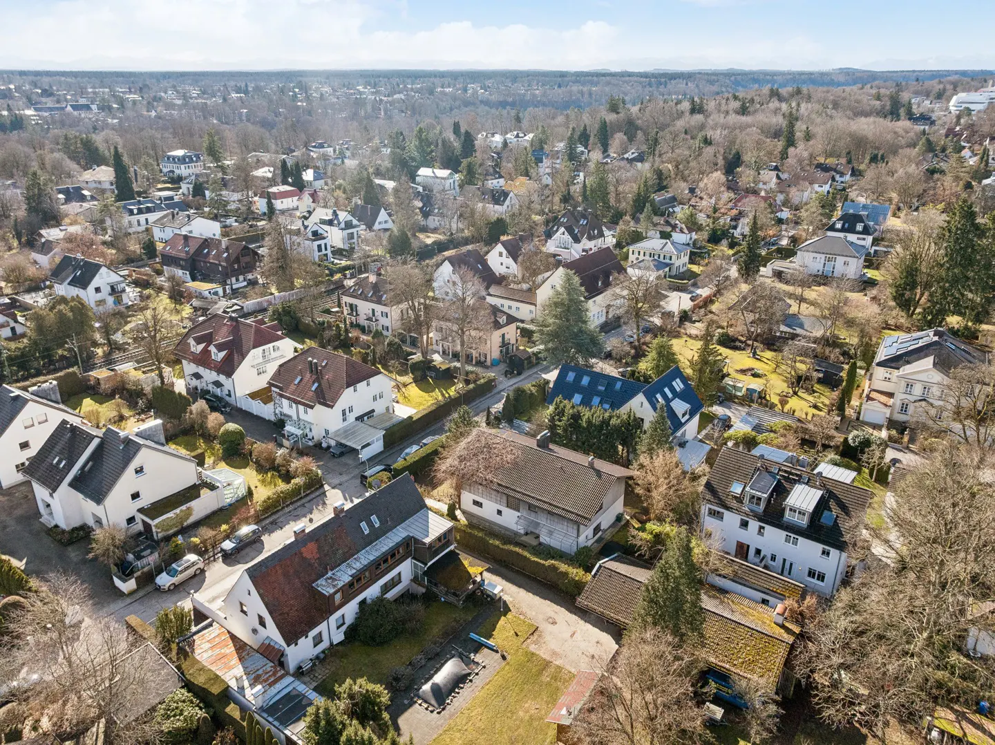 Aerial view of a residential neighborhood with houses, trees, and a blue sky.