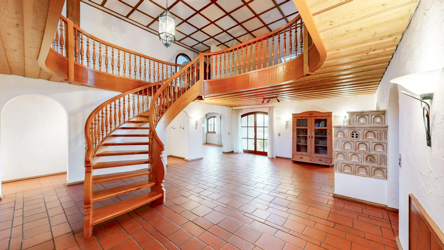 Interior view of a home featuring a wooden spiral staircase, terracotta tile flooring, and a wood-paneled ceiling.