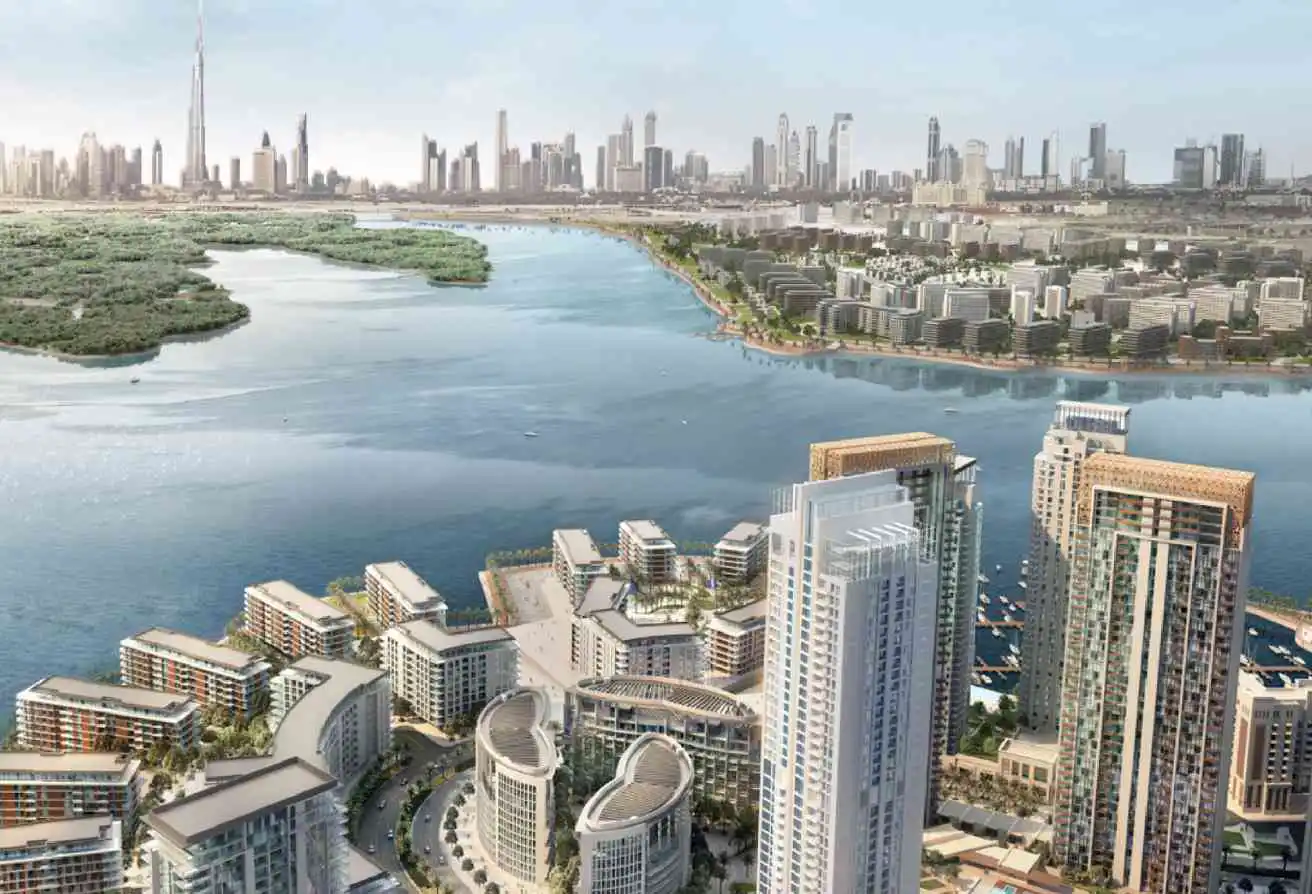 Aerial view of a modern waterfront residential complex in Dubai with the city skyline and Burj Khalifa in the background.