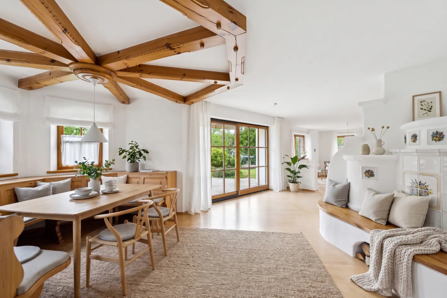Bright, open dining room with wood table, chairs, and built-in bench seating. Exposed wood beams on ceiling and a tiled fireplace with bench.