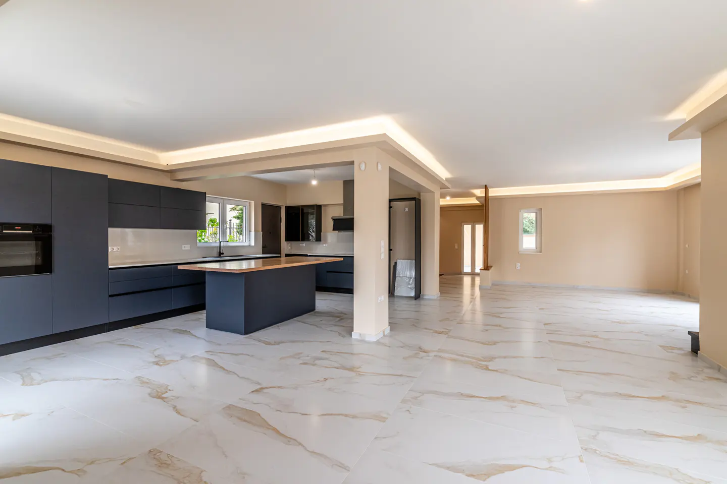 Open-concept kitchen and living area with marble floors, dark blue cabinets, and a wood-topped island.