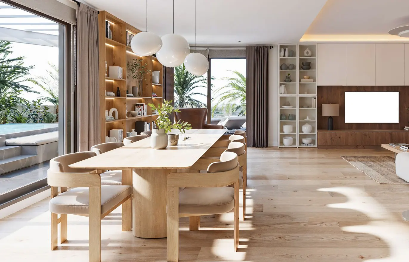 Bright, modern dining room with a light wood table and chairs. Large windows overlook a pool and palm trees. Shelves and a TV are in the background.