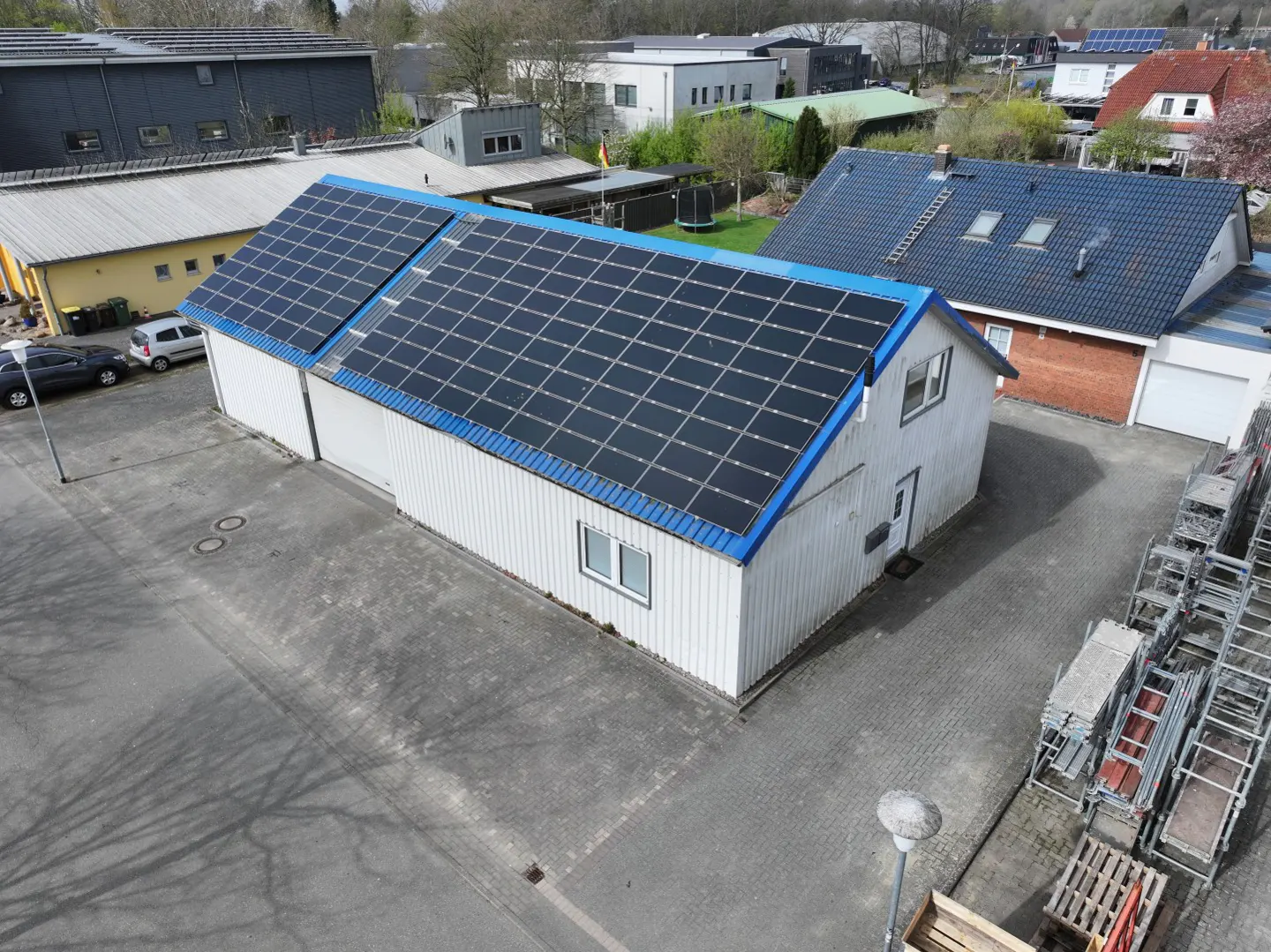 Aerial view of a white building with blue trim and solar panels on the roof.