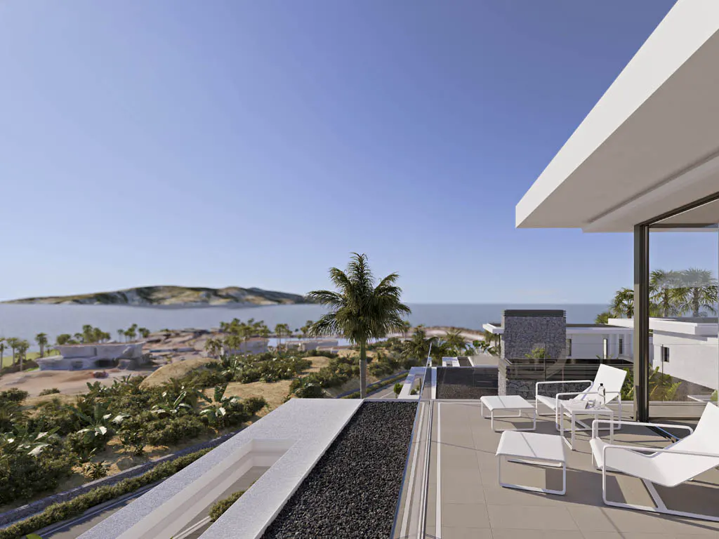 Balcony view of a modern white house with lounge chairs overlooking the ocean and island under a clear blue sky.