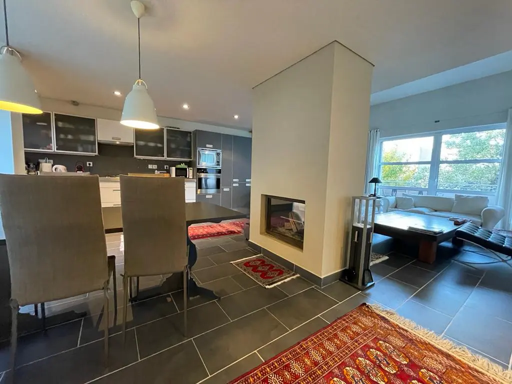 Open-concept kitchen and living room with gray tile flooring, a fireplace, and a large window.