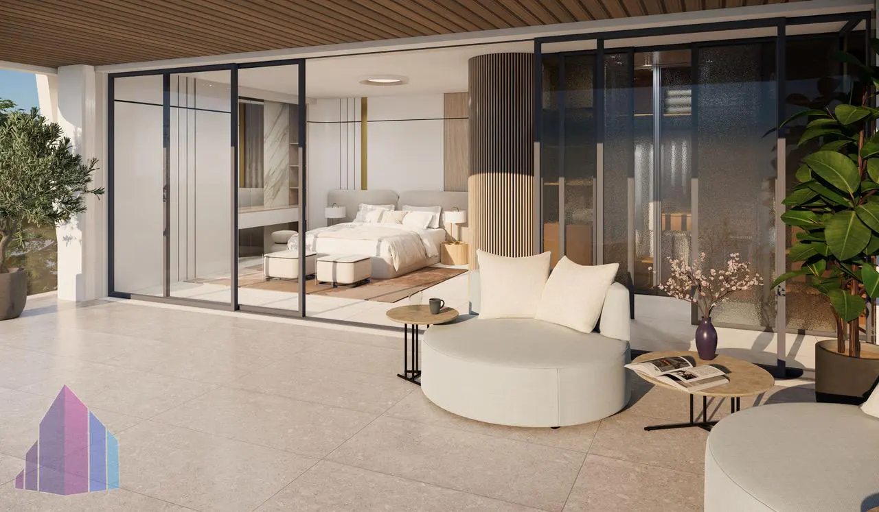 A modern bedroom with a patio featuring white circular seating, tables, and plants. The bedroom has a bed, vanity, and sliding glass doors.