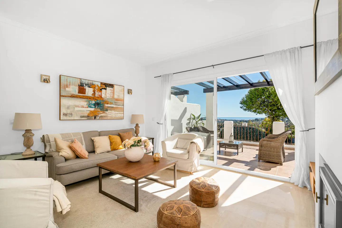Bright living room with a gray sofa, wood table, and open sliding doors to a patio with a view.