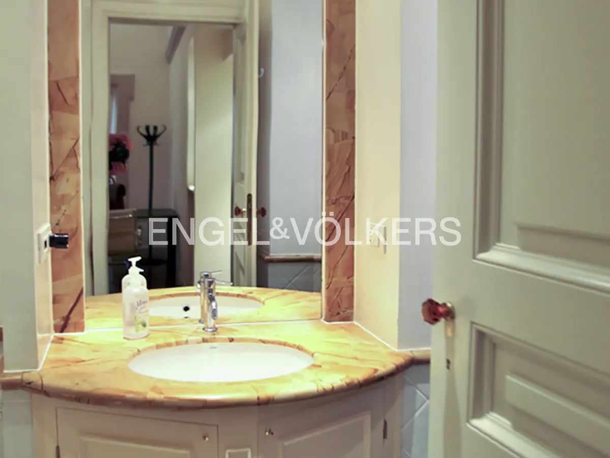 Bathroom vanity with a yellow marble countertop, white oval sink, chrome faucet, and a large mirror with marble trim.