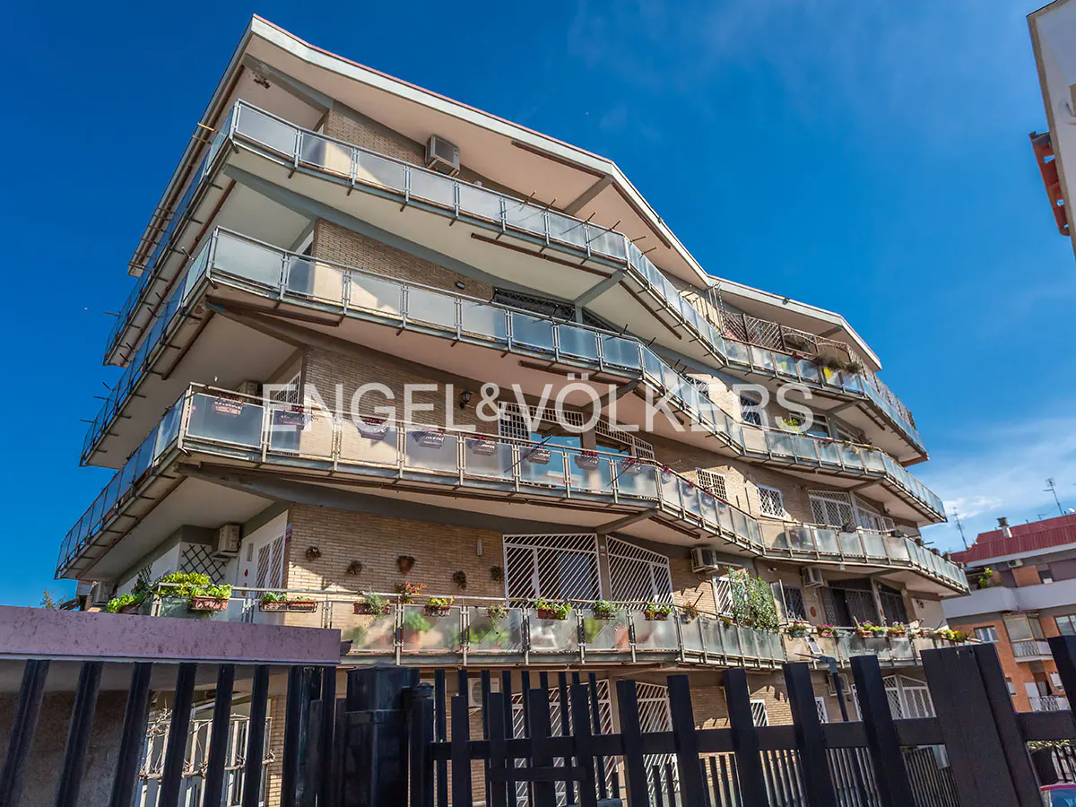 Exterior view of a multi-story apartment building with balconies, under a blue sky. The Engel & Völkers logo is visible on the building.