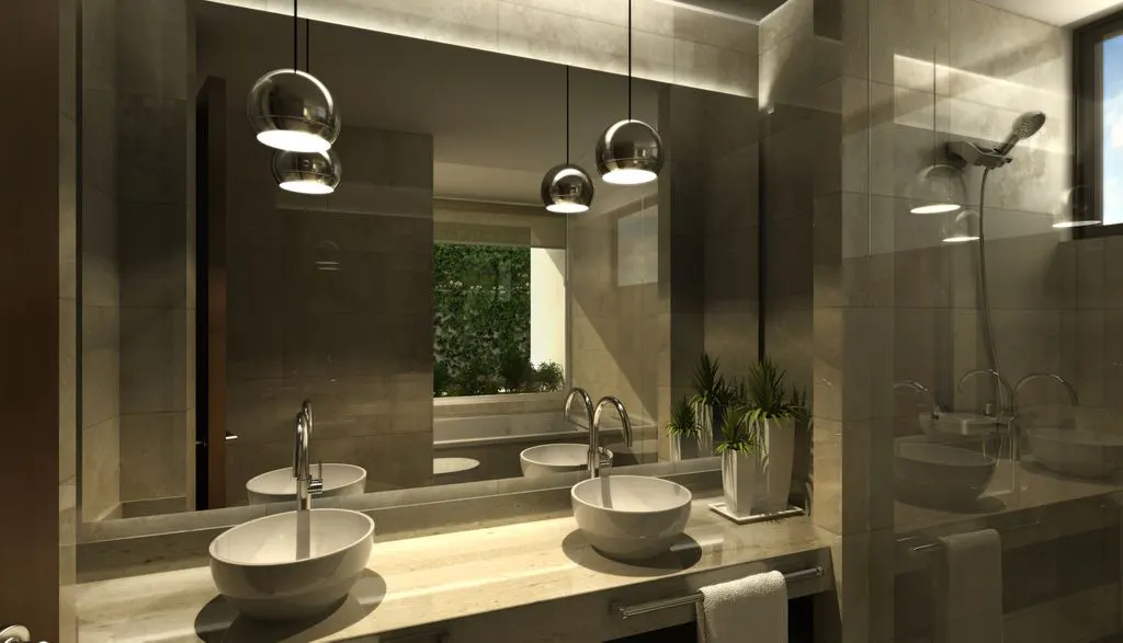 Modern bathroom with marble countertop, white vessel sinks, and chrome fixtures. A large mirror reflects pendant lights and greenery outside.