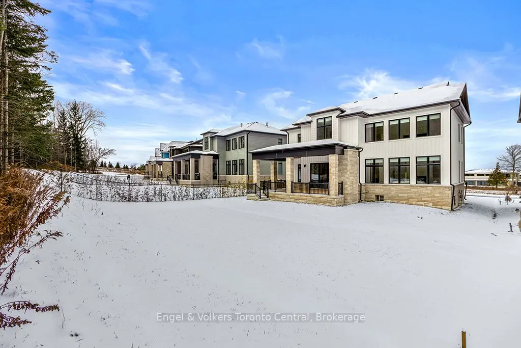 Row of modern homes with stone accents and covered porches, set against a snowy landscape under a blue sky.