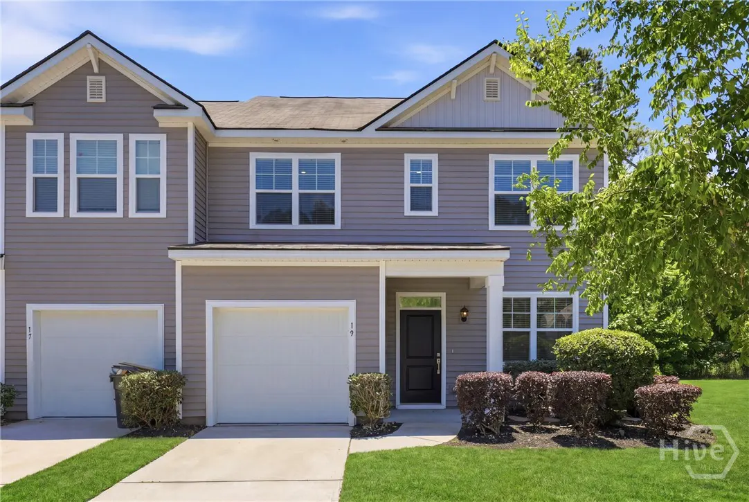 Two-story gray townhouse with white garage doors, black front door, and green lawn.