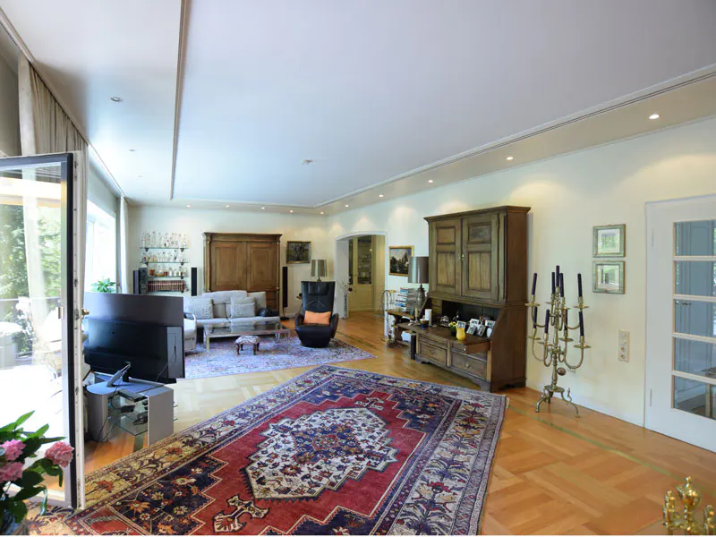 Spacious living room with hardwood floors, a red and blue rug, and antique wooden furniture.