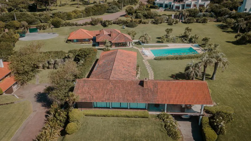 Aerial view of a large property with multiple buildings, a pool, and green lawns. The buildings have red tile roofs.