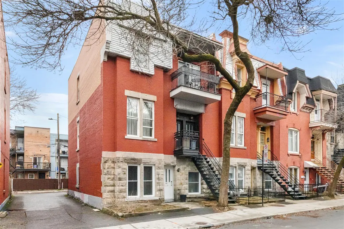 Exterior view of a three-story red brick apartment building with black metal stairs and balconies.