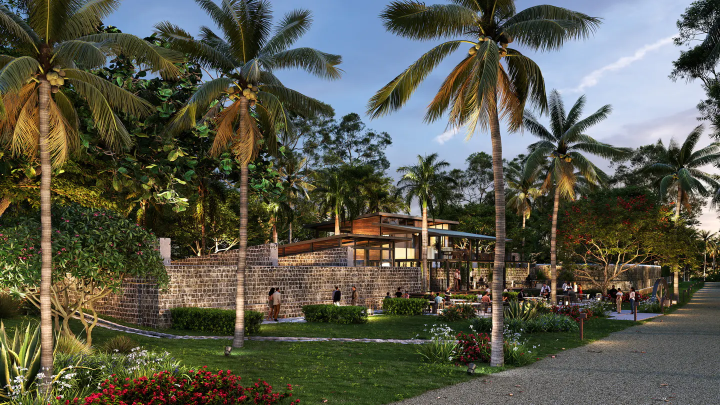 Outdoor restaurant with palm trees, stone walls, and people dining at tables. The sky is blue.