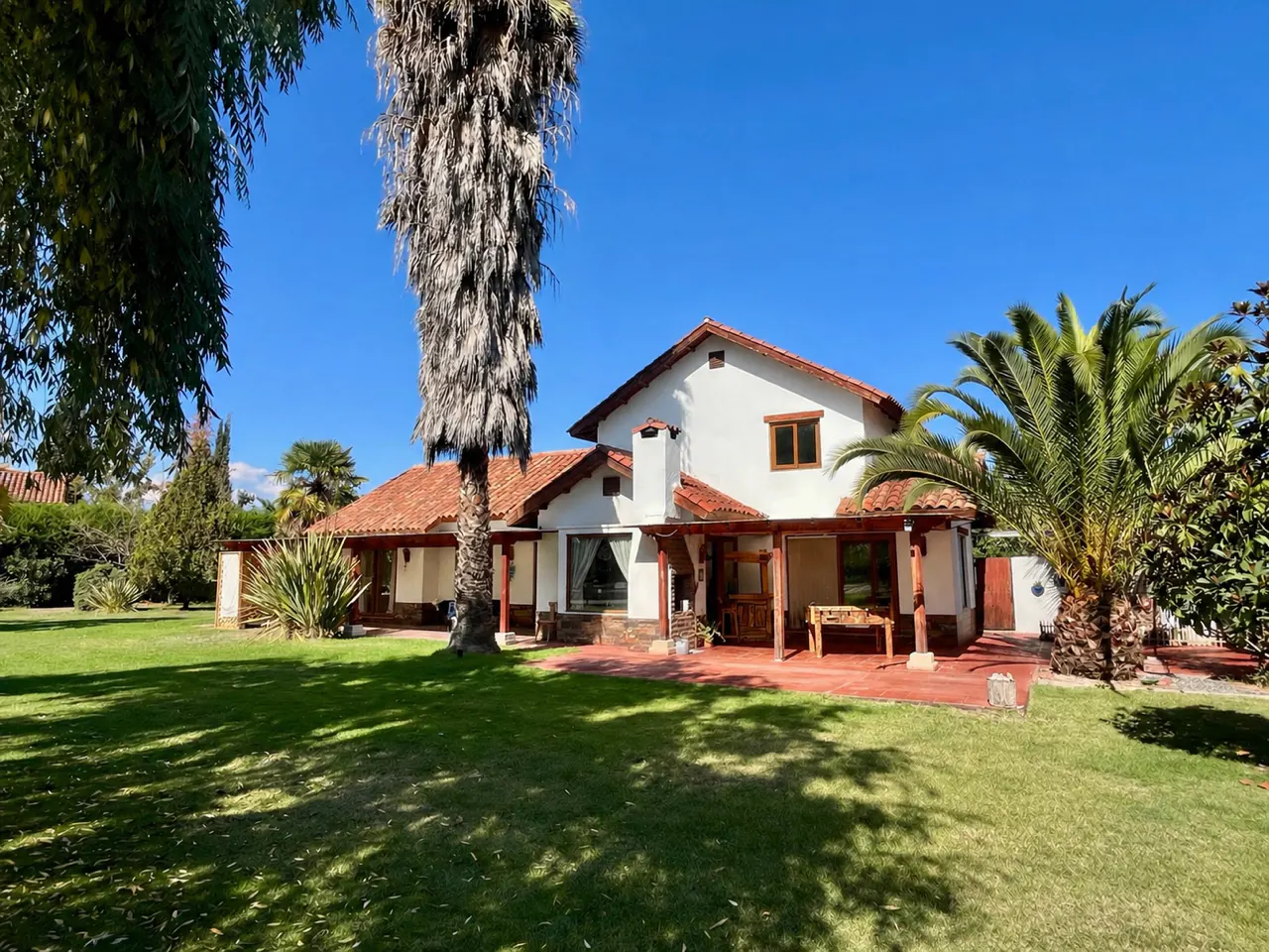 A white house with a red tile roof and a green lawn under a blue sky.