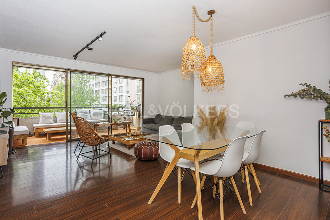 Modern dining area with glass table, white chairs, woven pendant lights, and a balcony view with dark wood flooring.