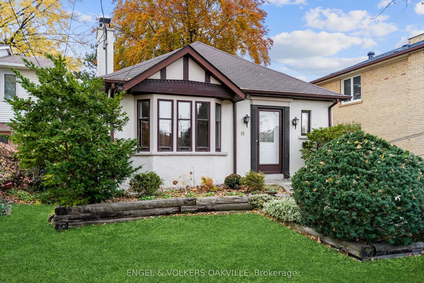 Exterior view of a one-story white house with brown trim, a bay window, and a well-manicured lawn.