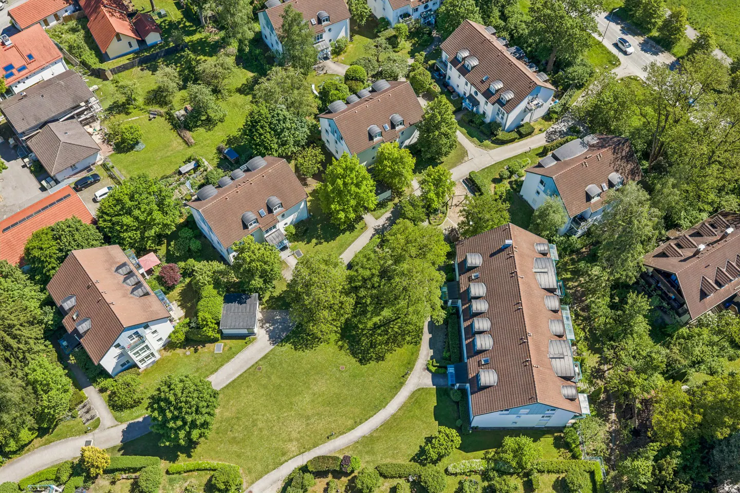 Aerial view of a residential neighborhood with multi-story apartment buildings, green lawns, and winding pathways.