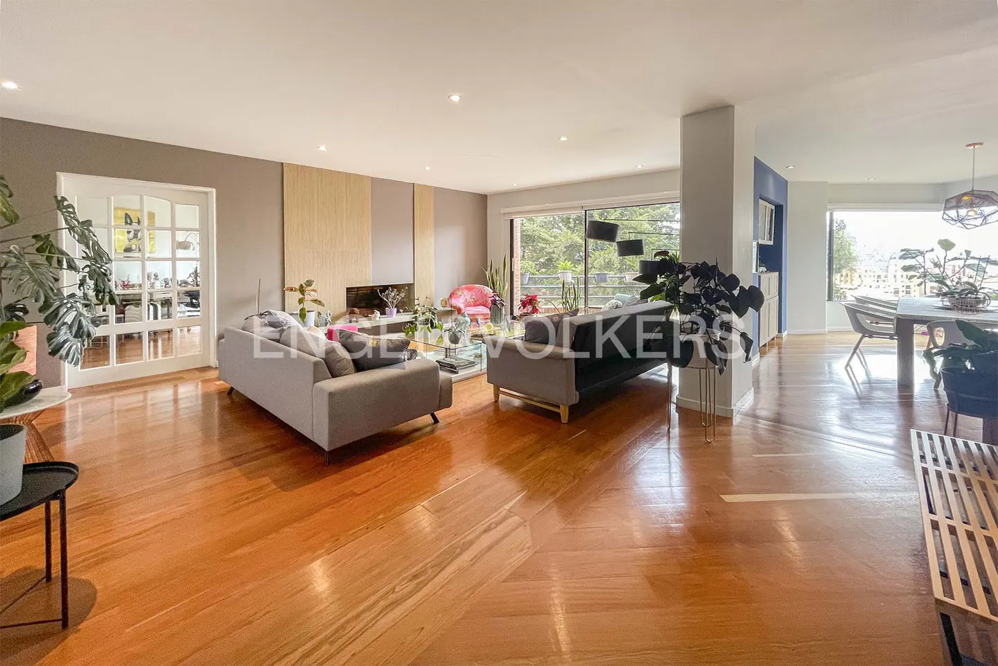Open-concept living room with hardwood floors, gray sofas, and large windows with a view.