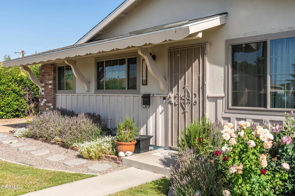 A single-story house with a beige exterior, a security door, and a well-maintained garden with lavender and roses.