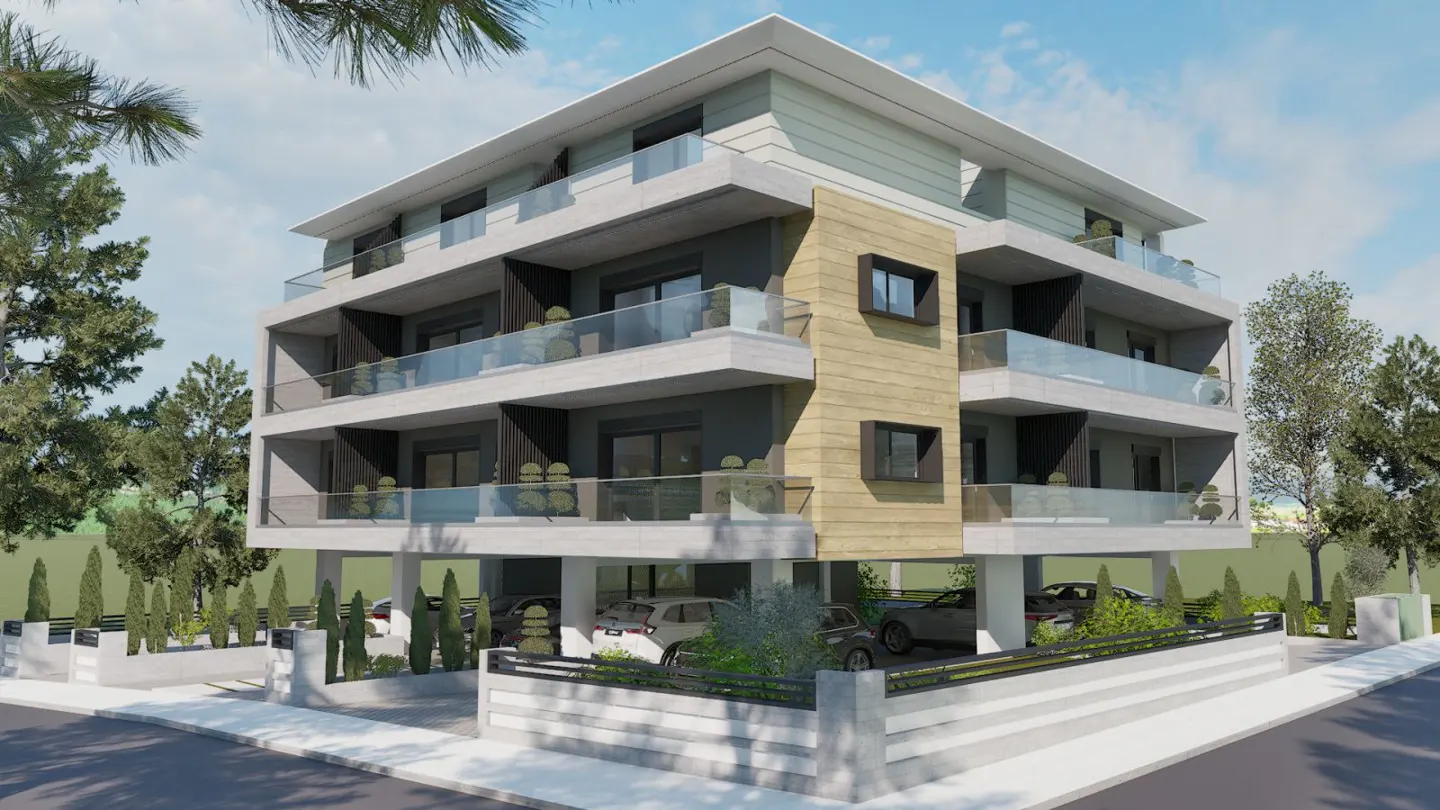 Modern three-story apartment building with balconies and parking. Gray and beige exterior with glass railings. Trees and blue sky in background.