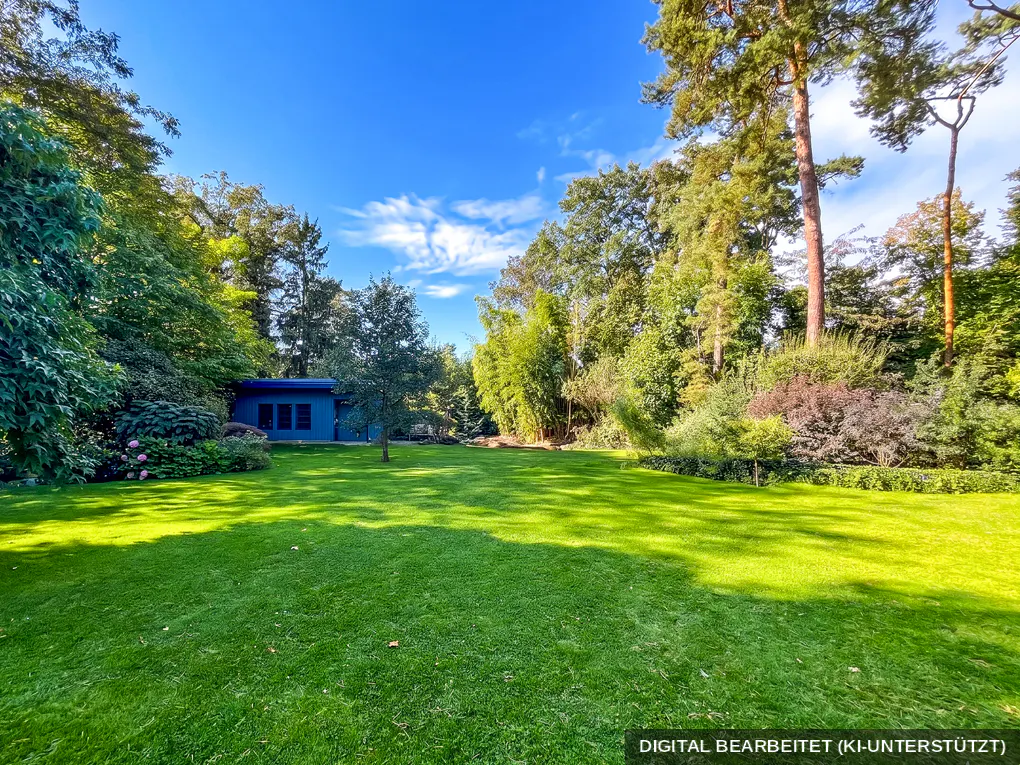 Lush green lawn with trees and a blue building under a bright blue sky.