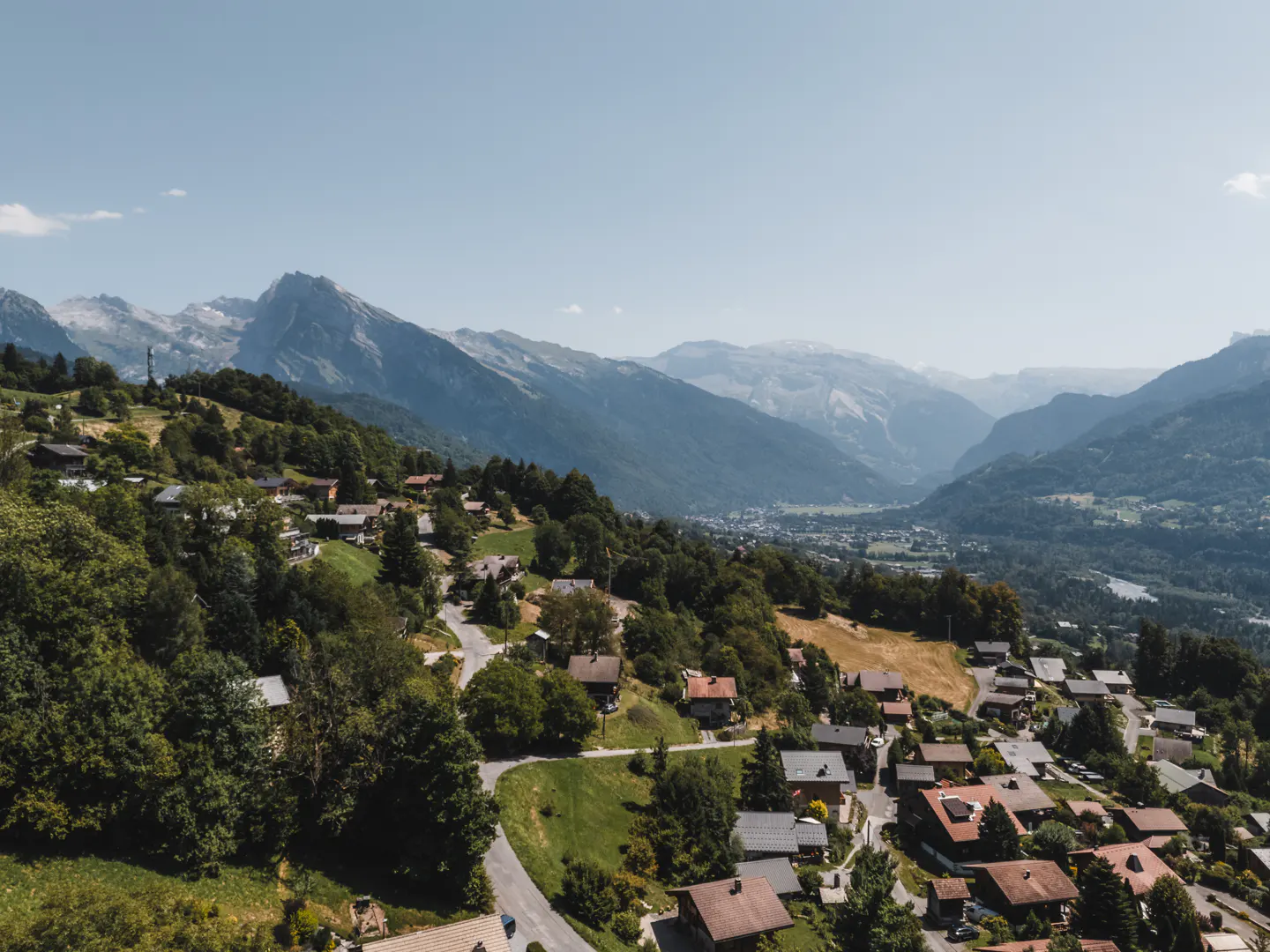 Scenic view of a village nestled in the mountains, featuring houses with red roofs and lush green trees.