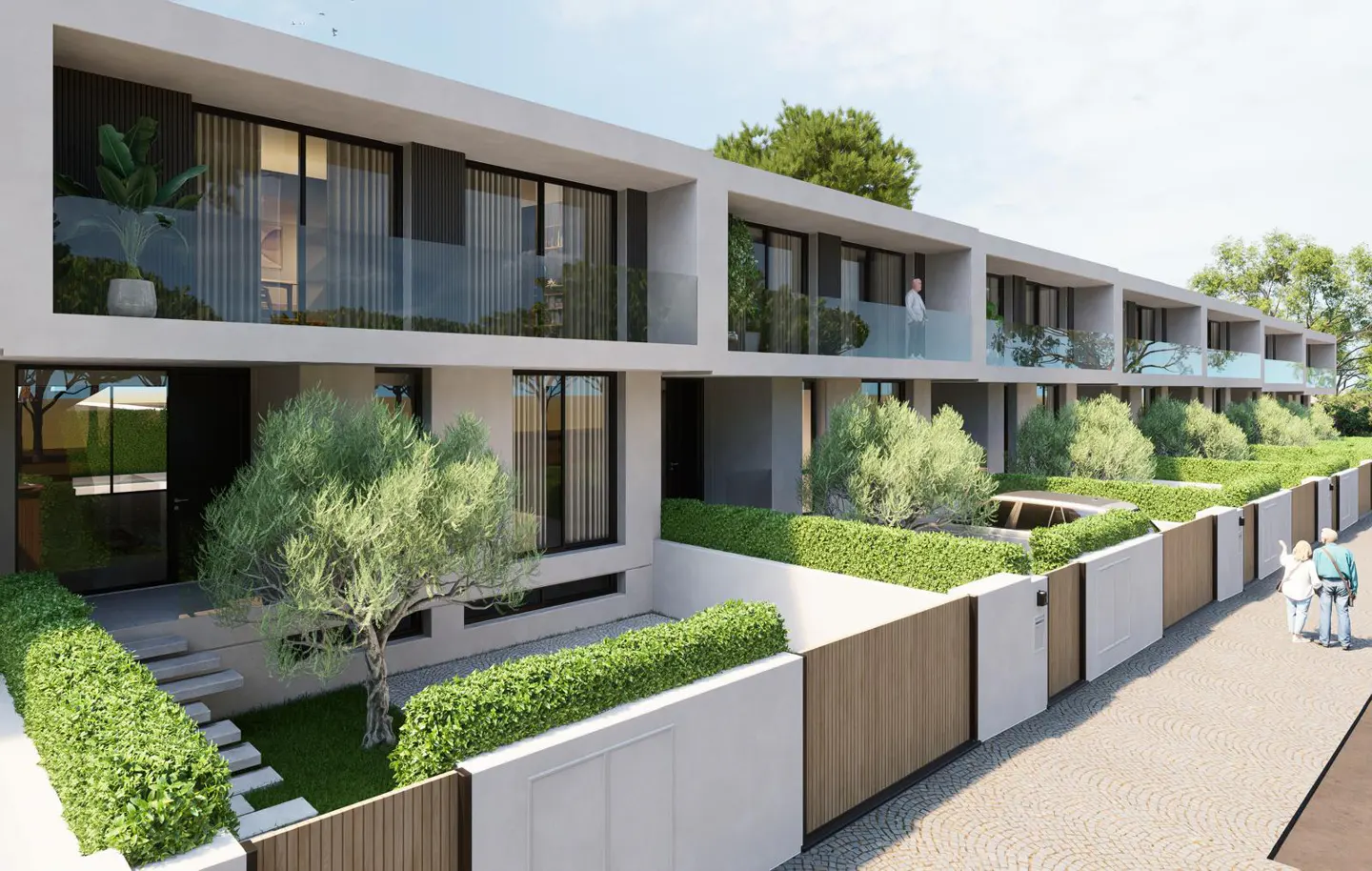 Row of modern townhouses with white exteriors, black framed windows, and wood fences. Green hedges and trees line the front yards.