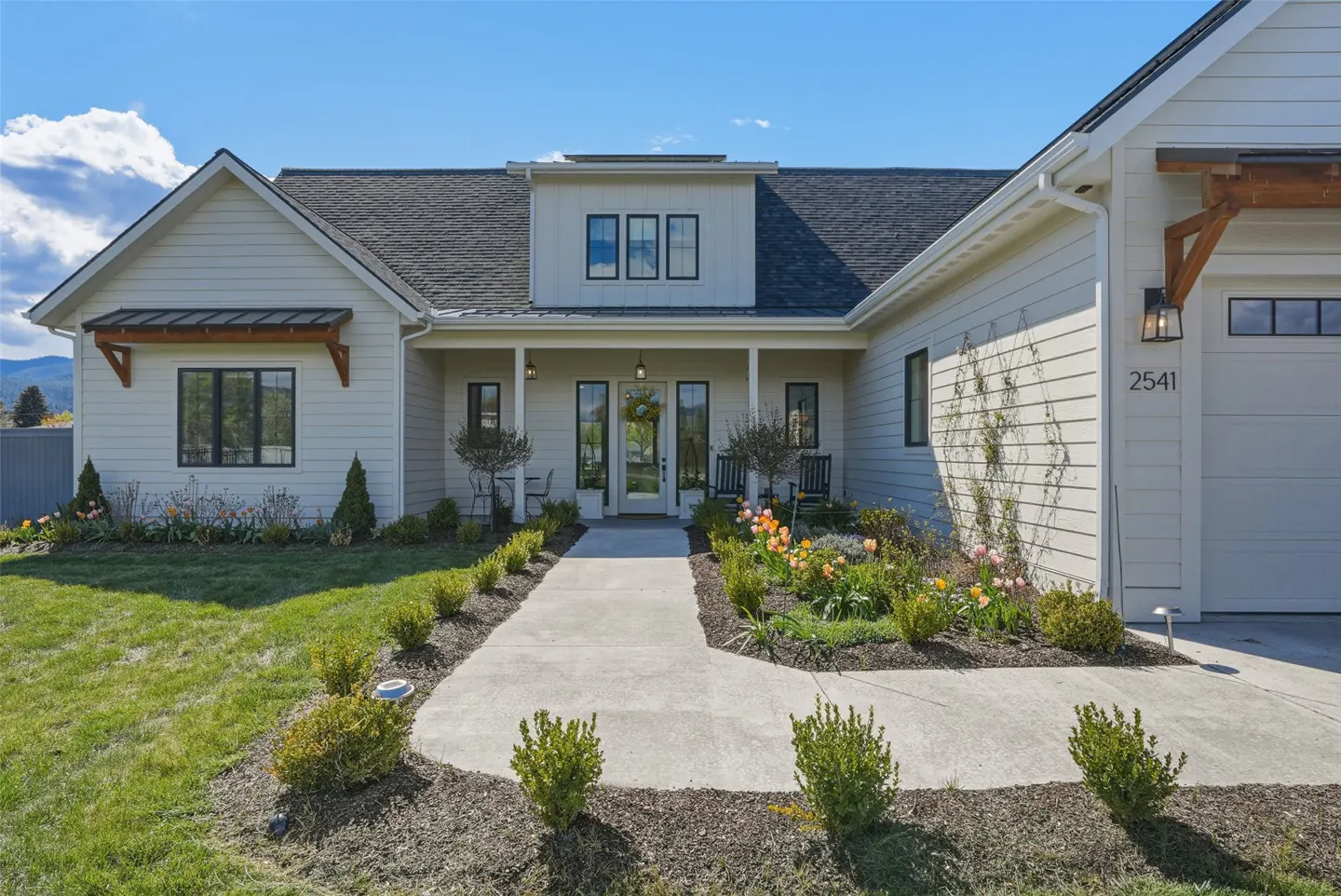 A single-story home with white siding, a gray roof, and a concrete walkway leading to the front door.