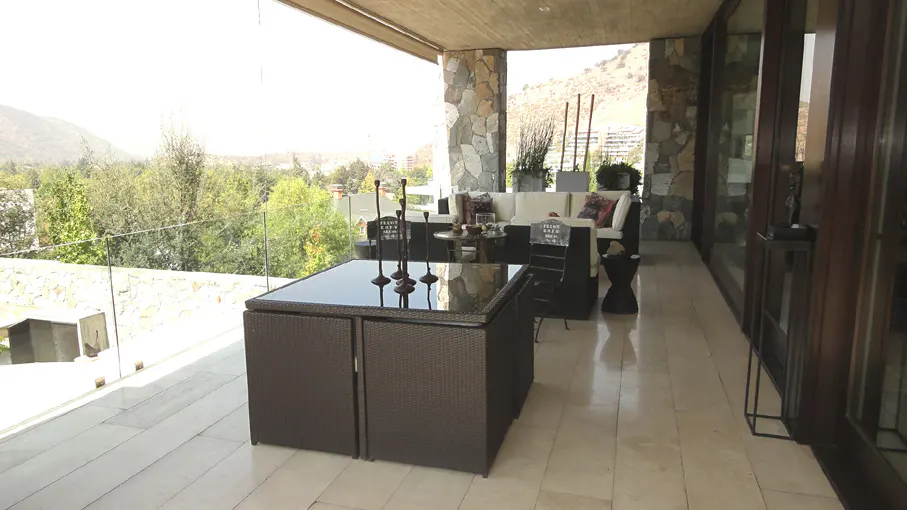 Outdoor patio with brown wicker furniture, glass railing, and mountain view.