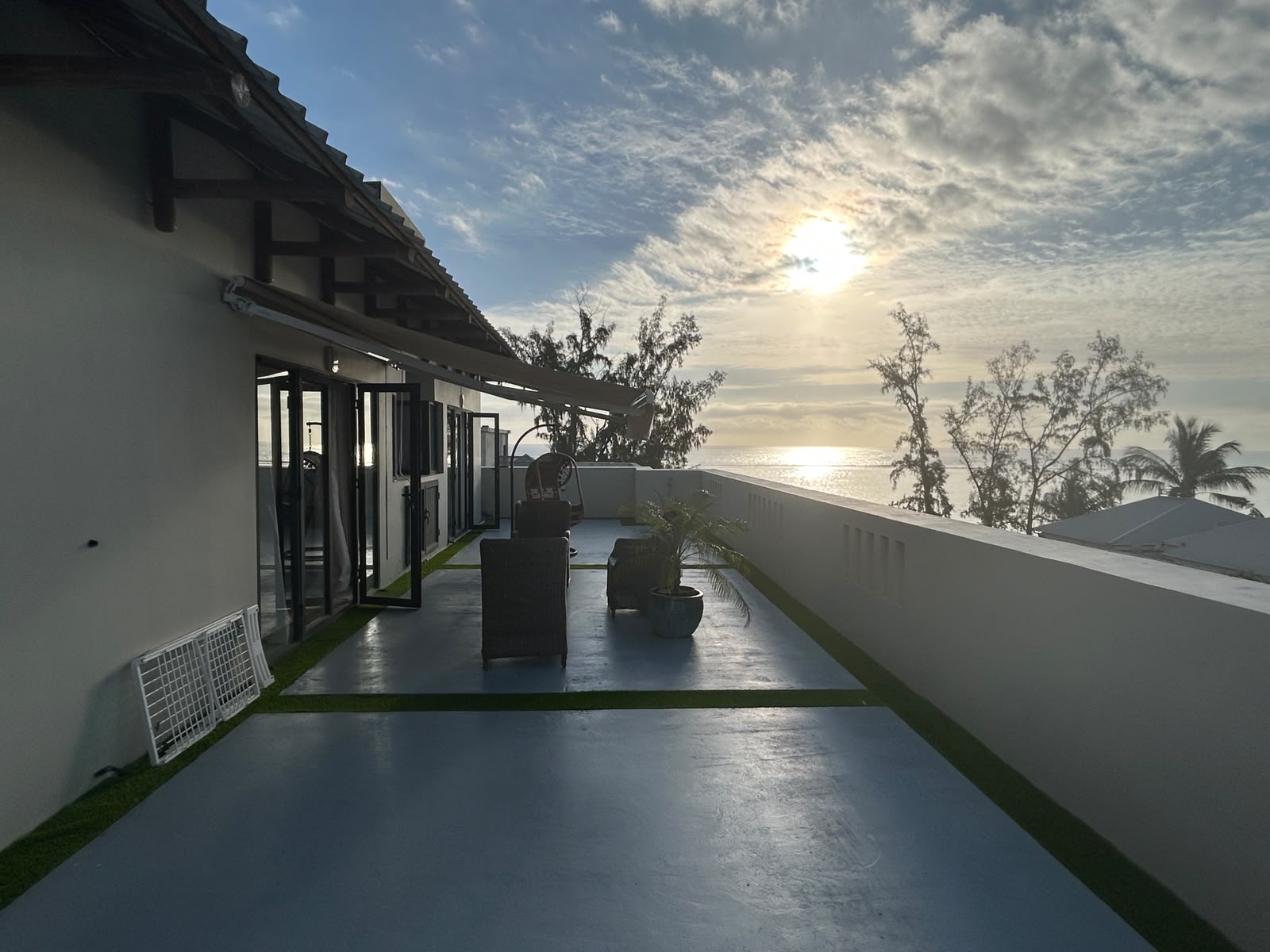 Spacious rooftop terrace with outdoor furniture overlooking the ocean at sunset. [AI-generated text]