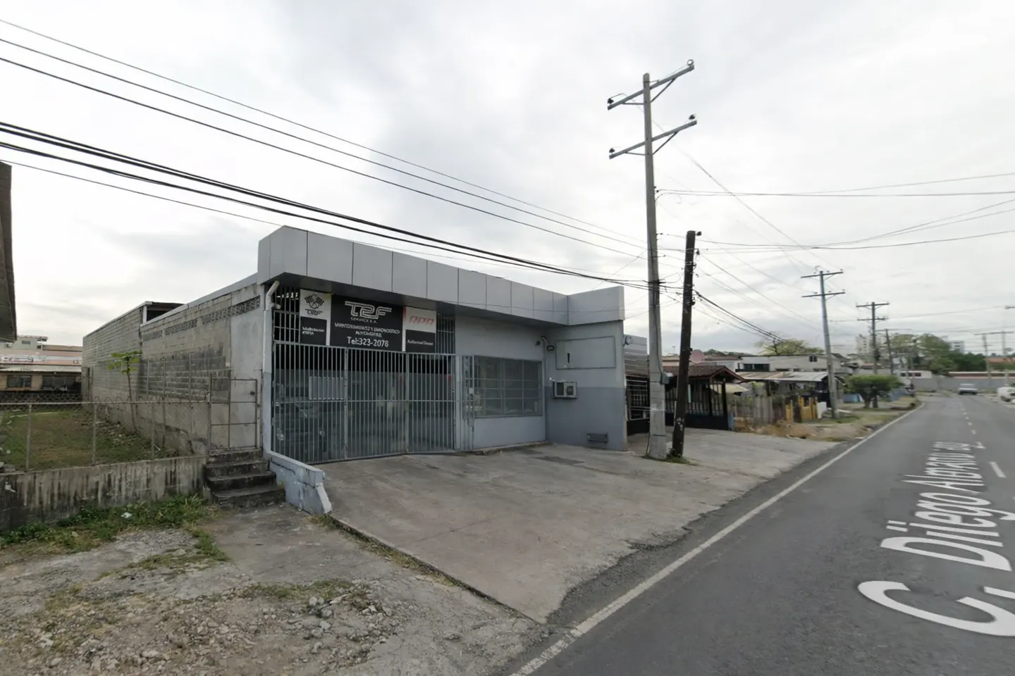 Exterior view of a gray, one-story commercial building with a gated entrance and a sign for TRF Automotive.