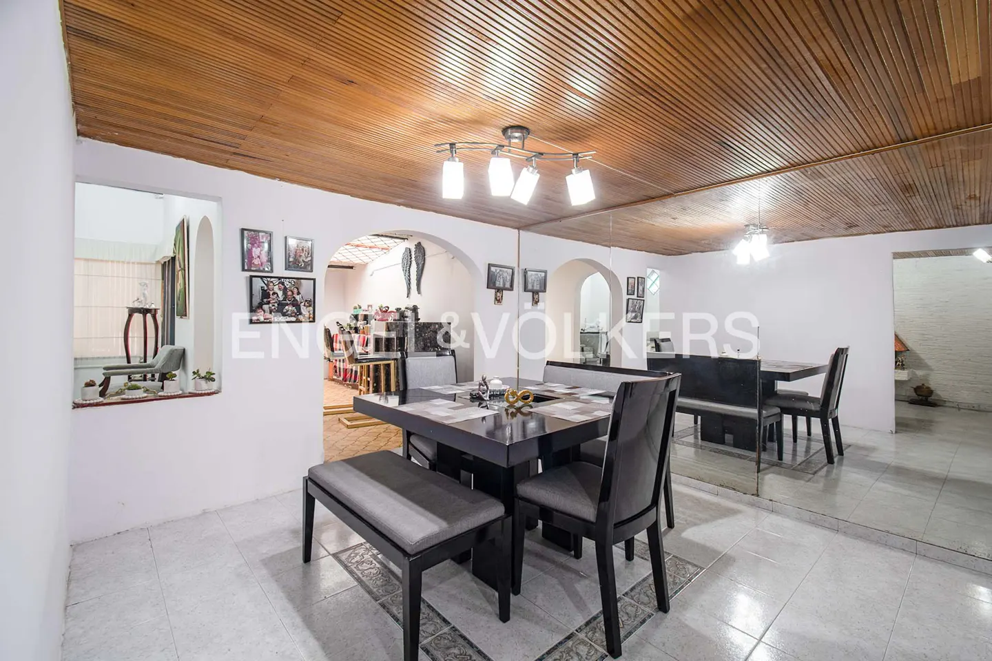 A dining room with a dark wood table, gray chairs, and a bench under a wood plank ceiling.