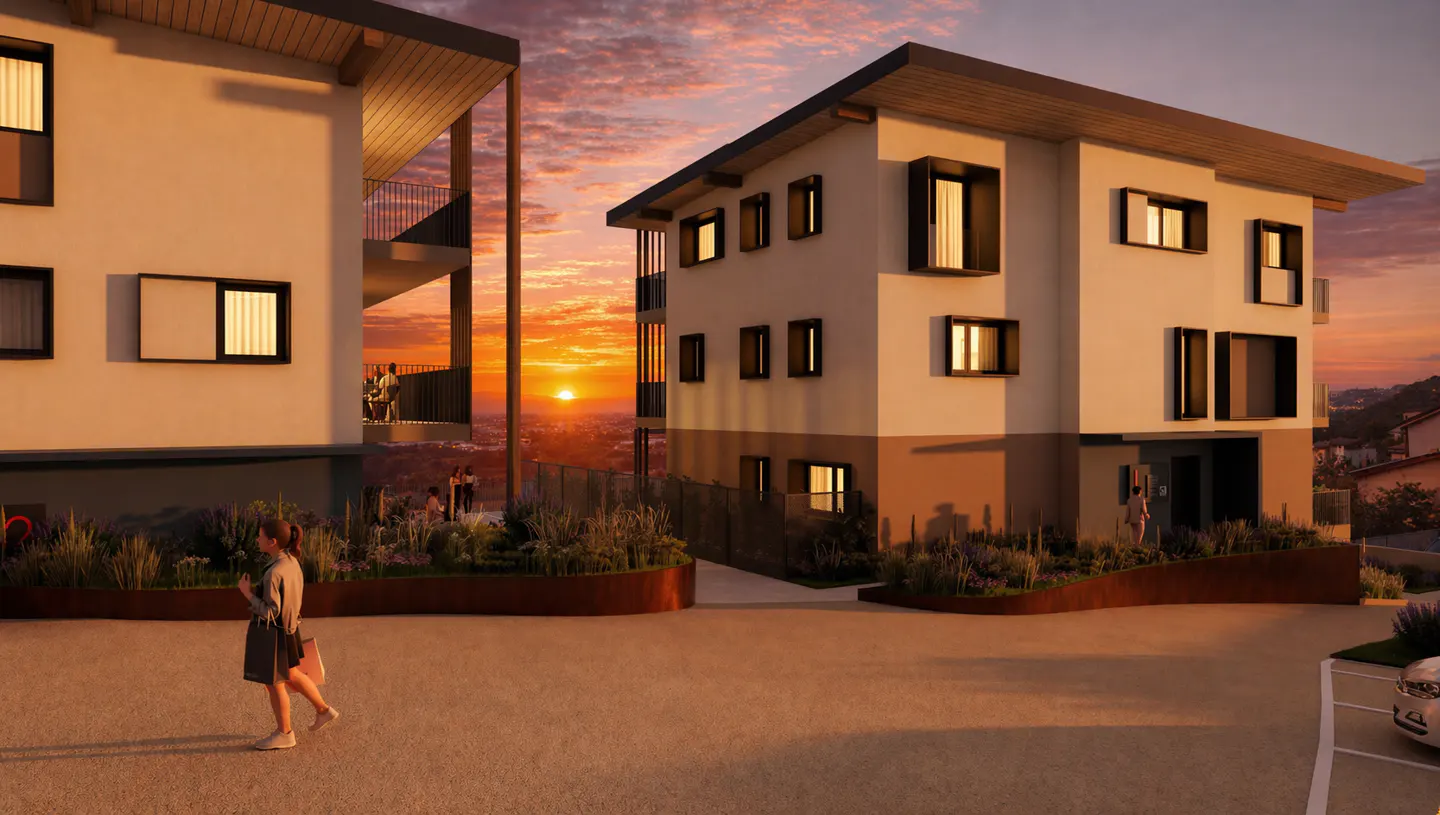Modern two-story apartment buildings with flat roofs at sunset. A woman walks in the foreground. Balconies and landscaping are visible.