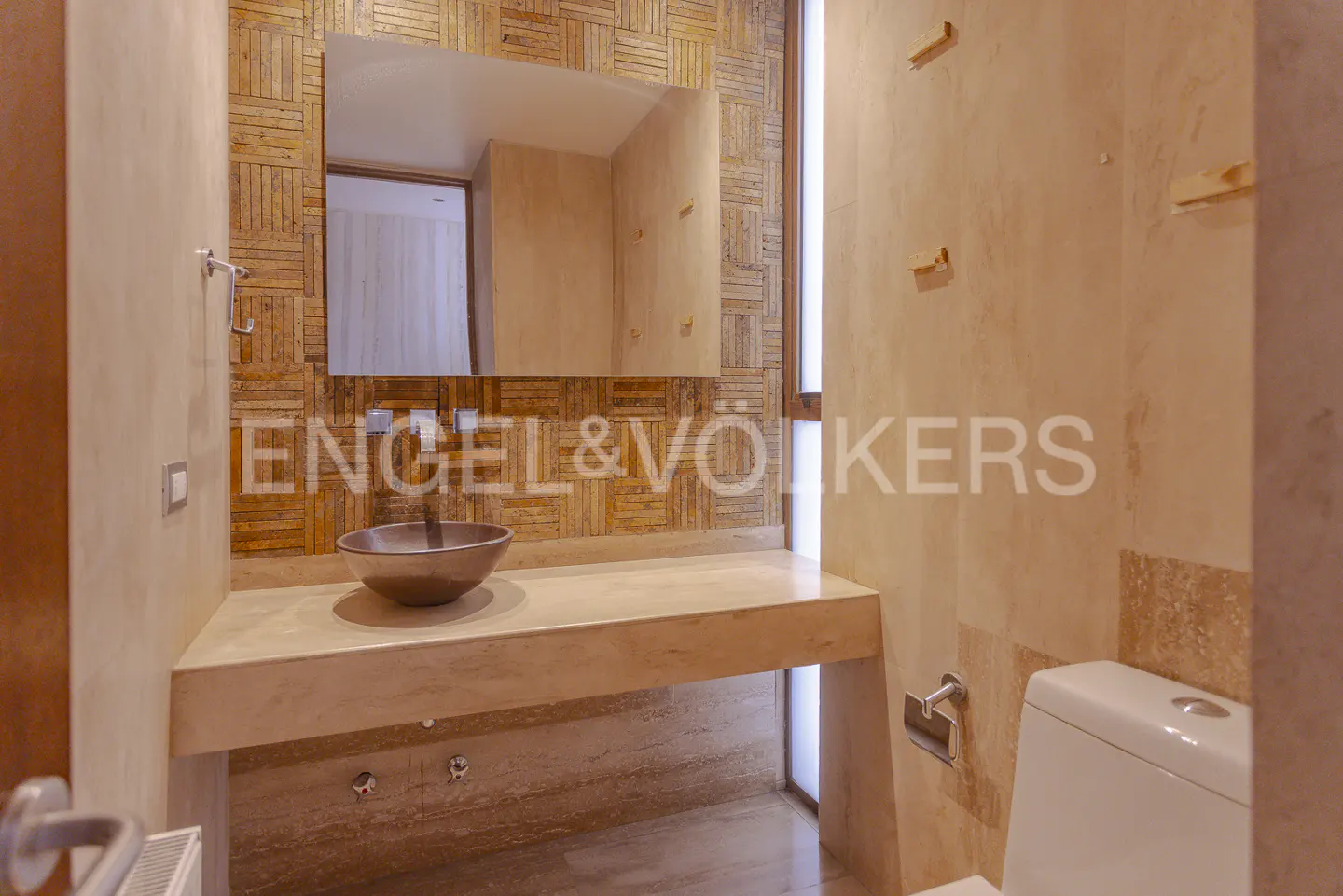 Bathroom with a brown sink, a mirror with a wooden frame, and a white toilet. The walls are beige.