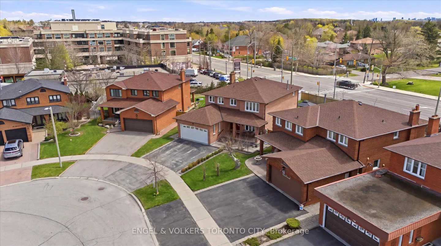 Aerial view of a residential neighborhood with brick houses, brown roofs, green lawns, and a street intersection.