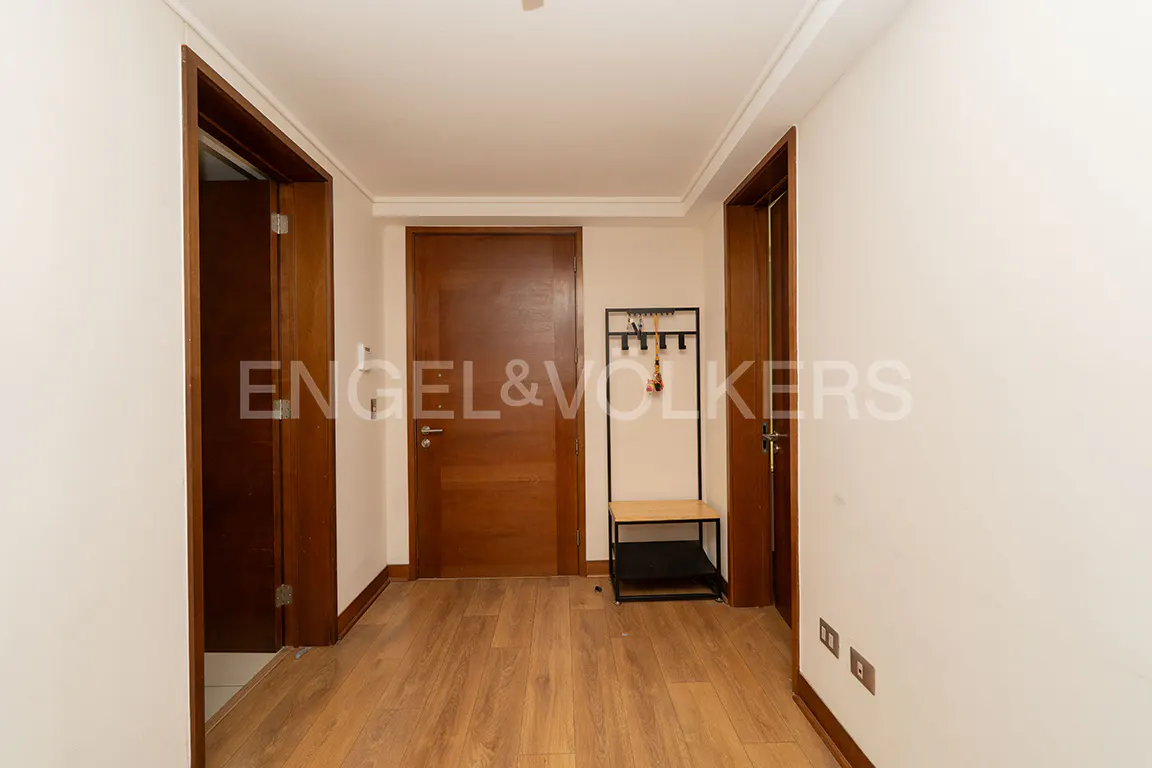 Entryway with wood floors, white walls, and brown doors. A black coat rack with a bench sits against the wall.