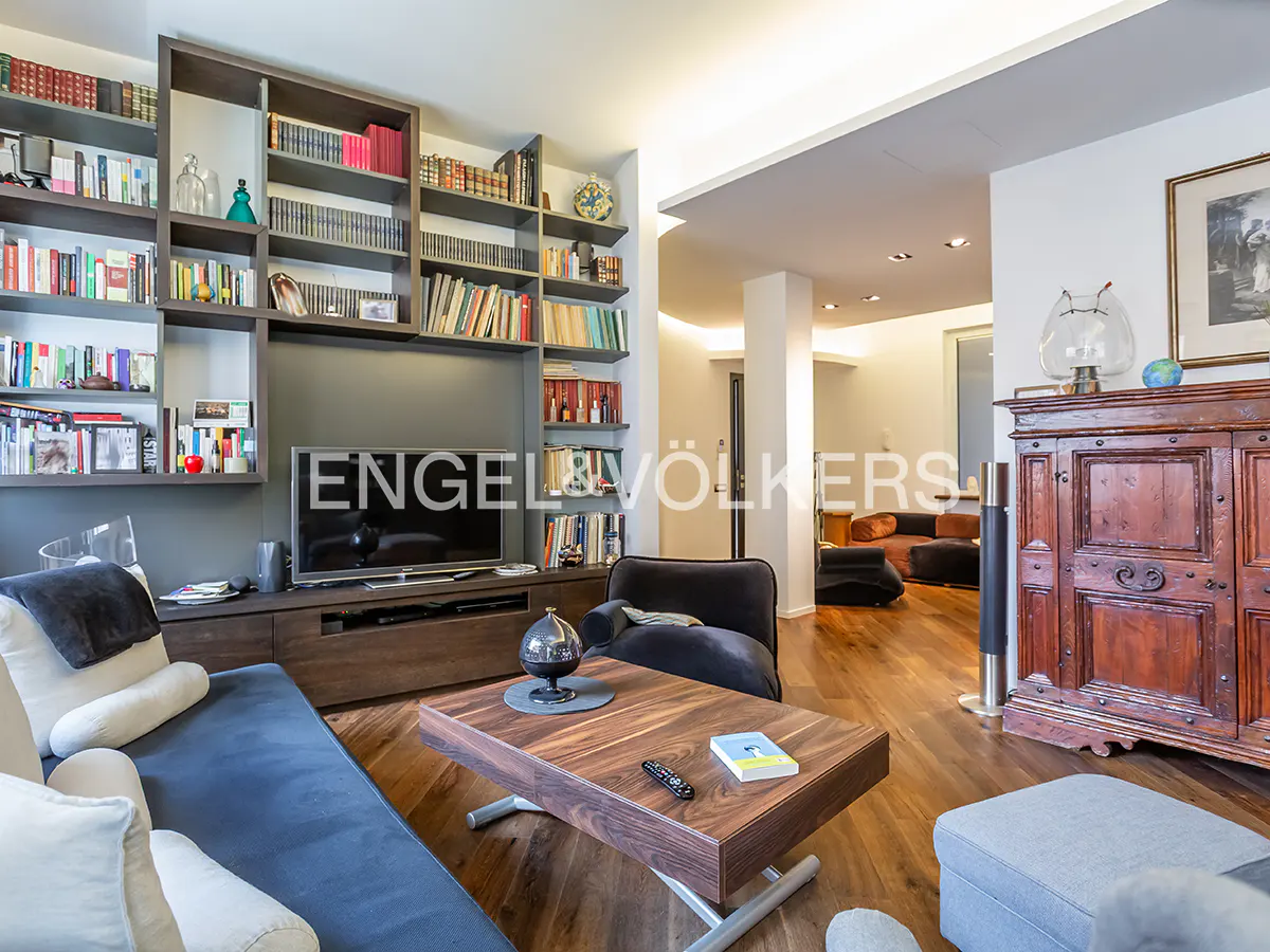 Living room with hardwood floors, a blue sofa, a wooden coffee table, and a large bookcase filled with books.