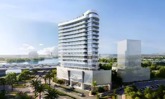 Modern white high-rise building with curved balconies, palm trees, and a bridge with cars in the background.