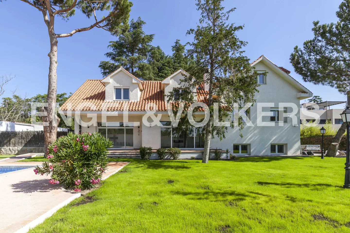 Exterior of a white two-story house with a red tile roof and green lawn on a sunny day.